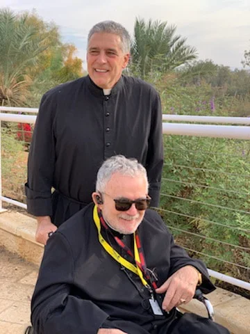 Father Mark Beard standing with a fellow priest during a ministry trip